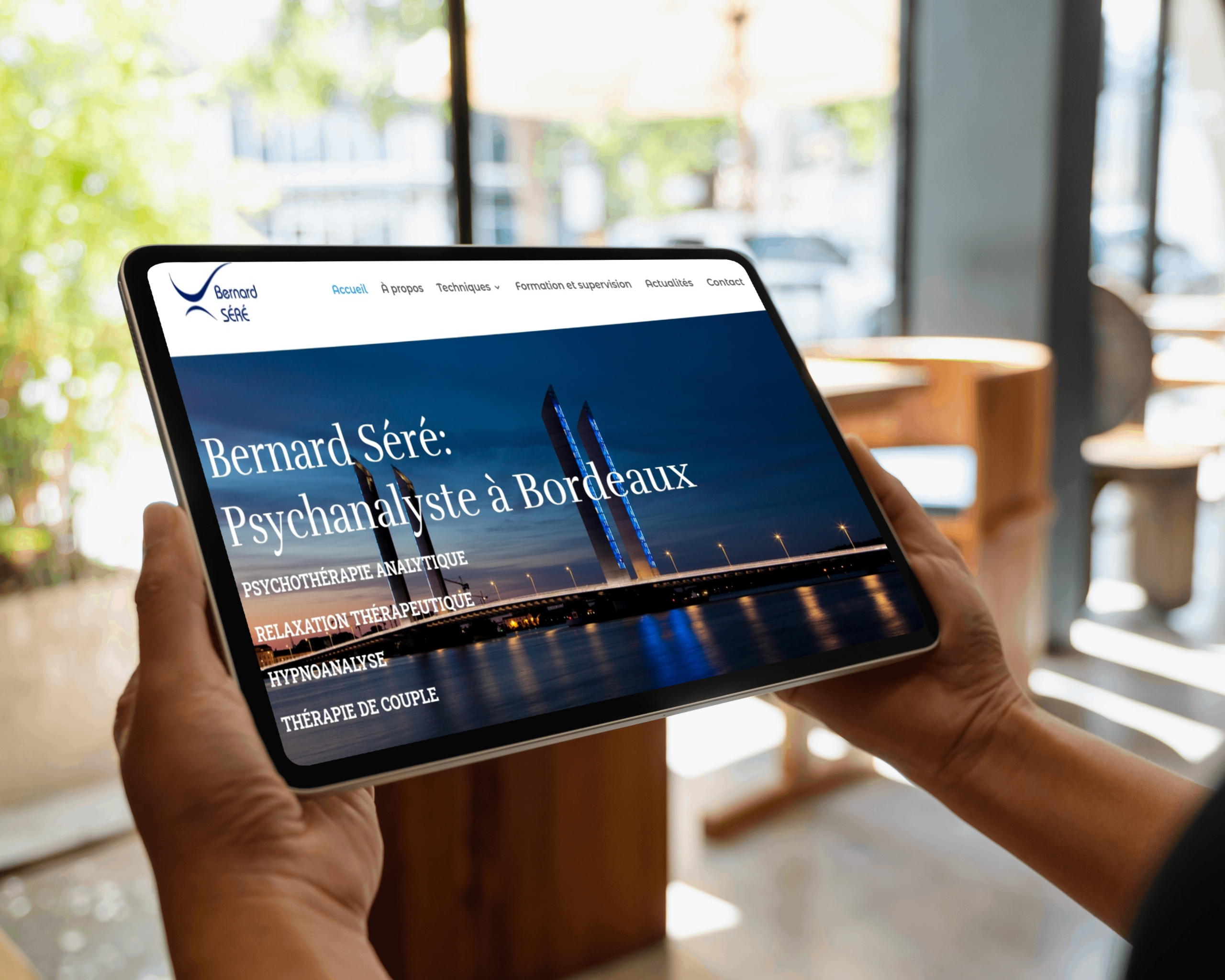 Mains d'homme qui tient une tablette avec visuel d'un de nos sites internet